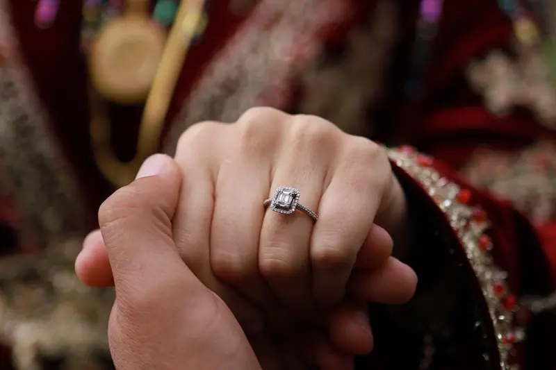 Halo engagement ring on a bride's hand, held by her partner