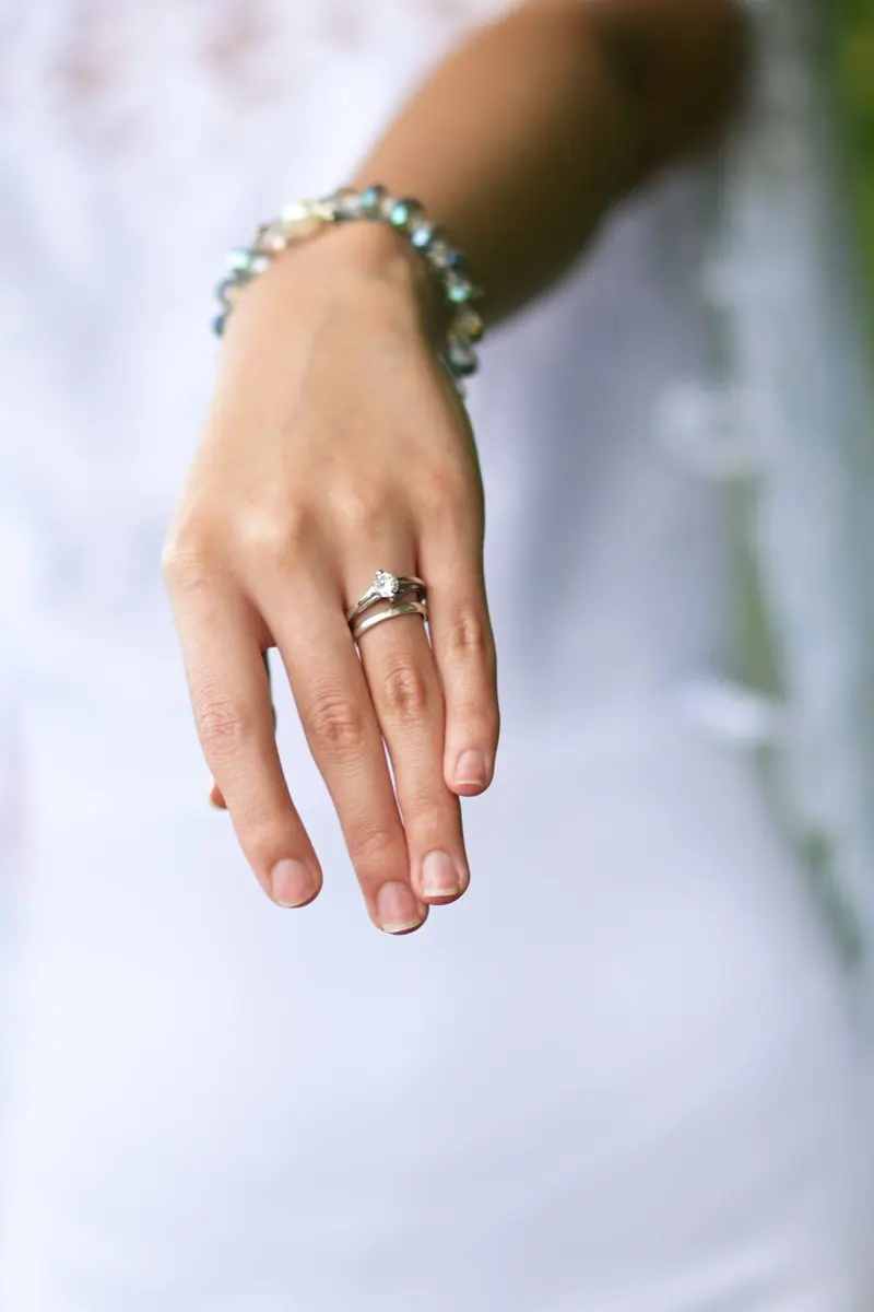 Hand wearing a diamond engagement ring and wedding band
